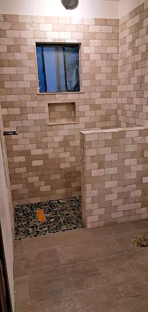 Travertine tile shower with pebble floor